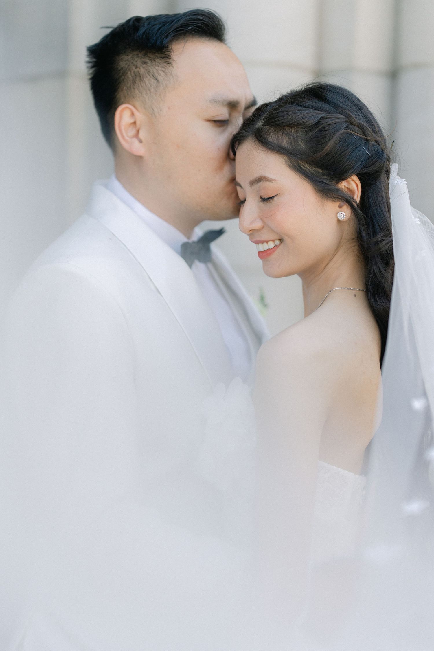 bride and groom standing together with a white floral bouquet during a classic wedding portrait