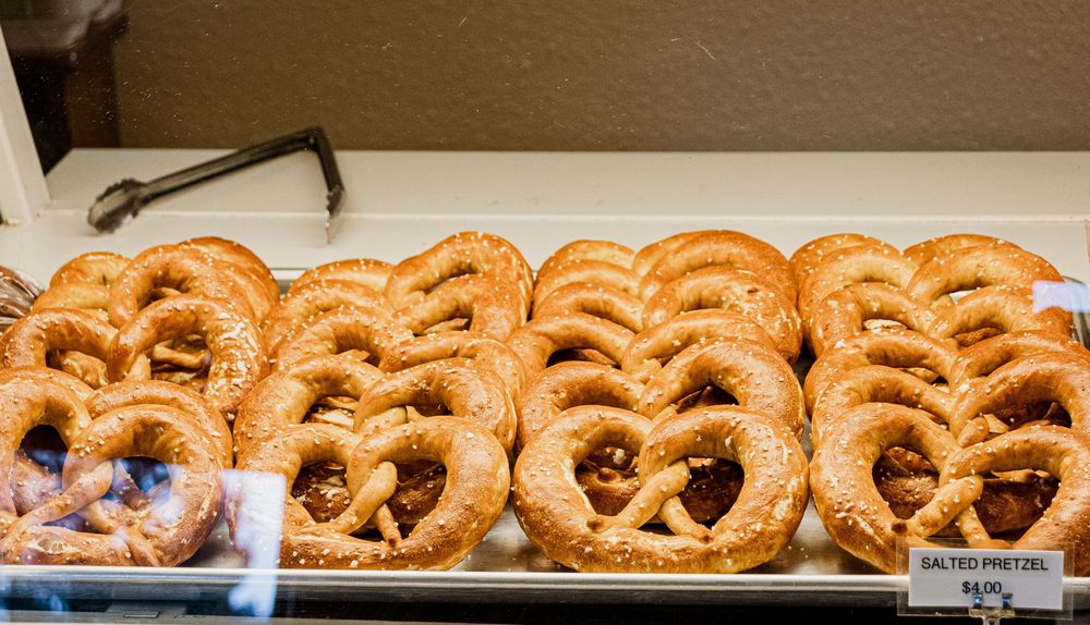 Fresh baked golden pretzels arranged in neat rows at a bakery display counter.