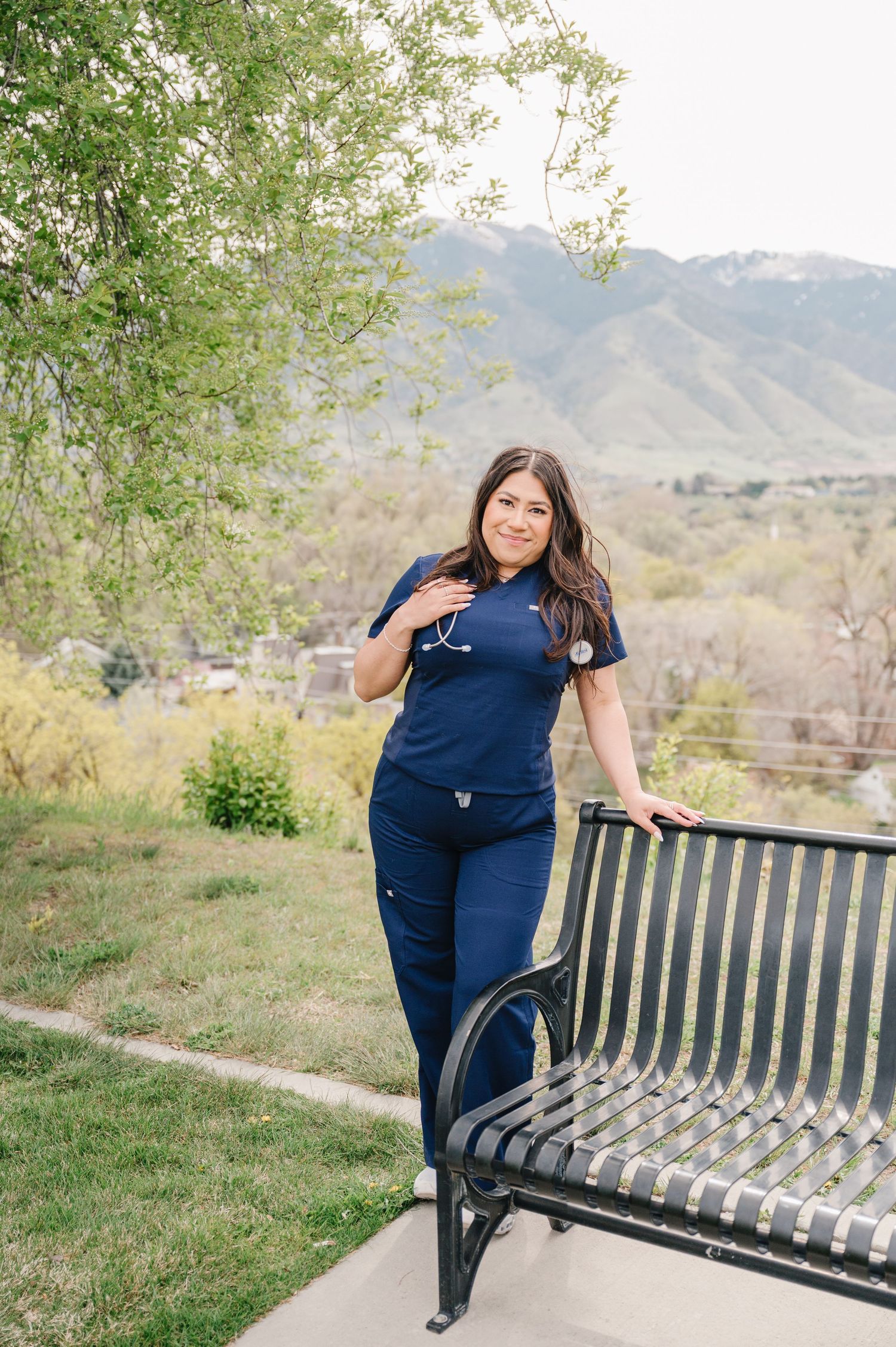 Outdoor scene with a park bench against mountain backdrop and greenery on a sunny spring day.