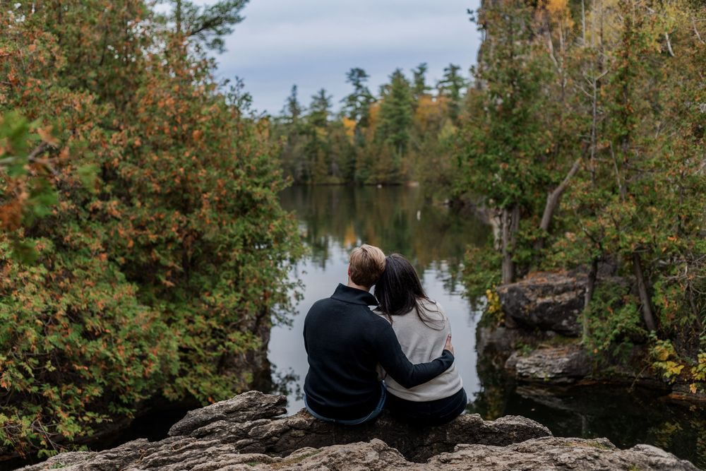 Couple sitting together during their engagement session atop the rocks at the rockwood conservation area in rockwood, ontario