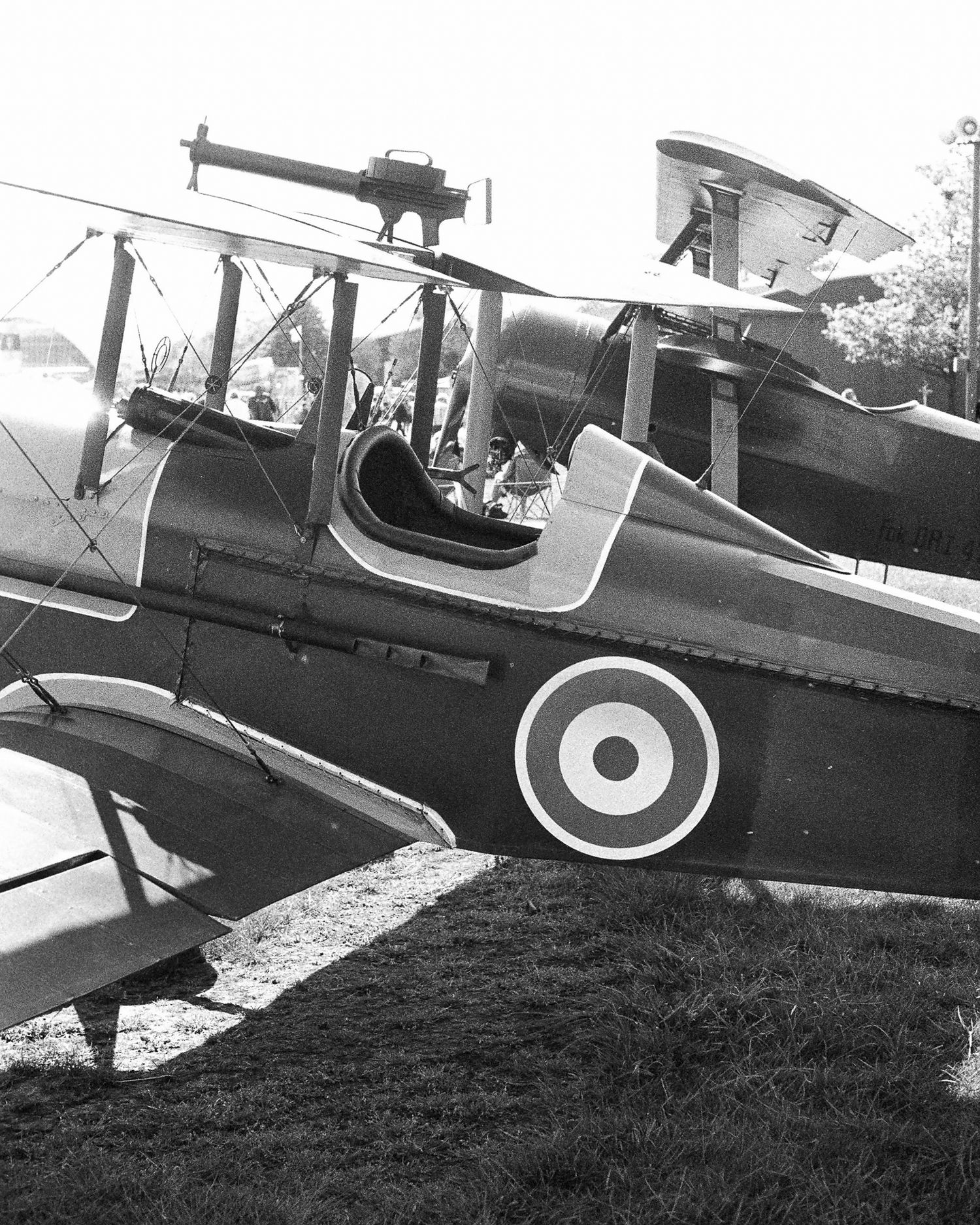 Vintage WWI biplane with RAF roundel markings on display outdoors, black and white photograph.