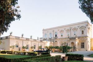 Elegant neoclassical villa with manicured hedges and lush gardens at dusk, perfect for luxury weddings in Italy.