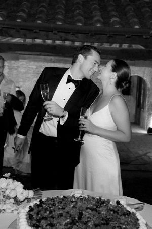 Black and white photo of a bride and groom sharing a toast with champagne glasses at their wedding reception.