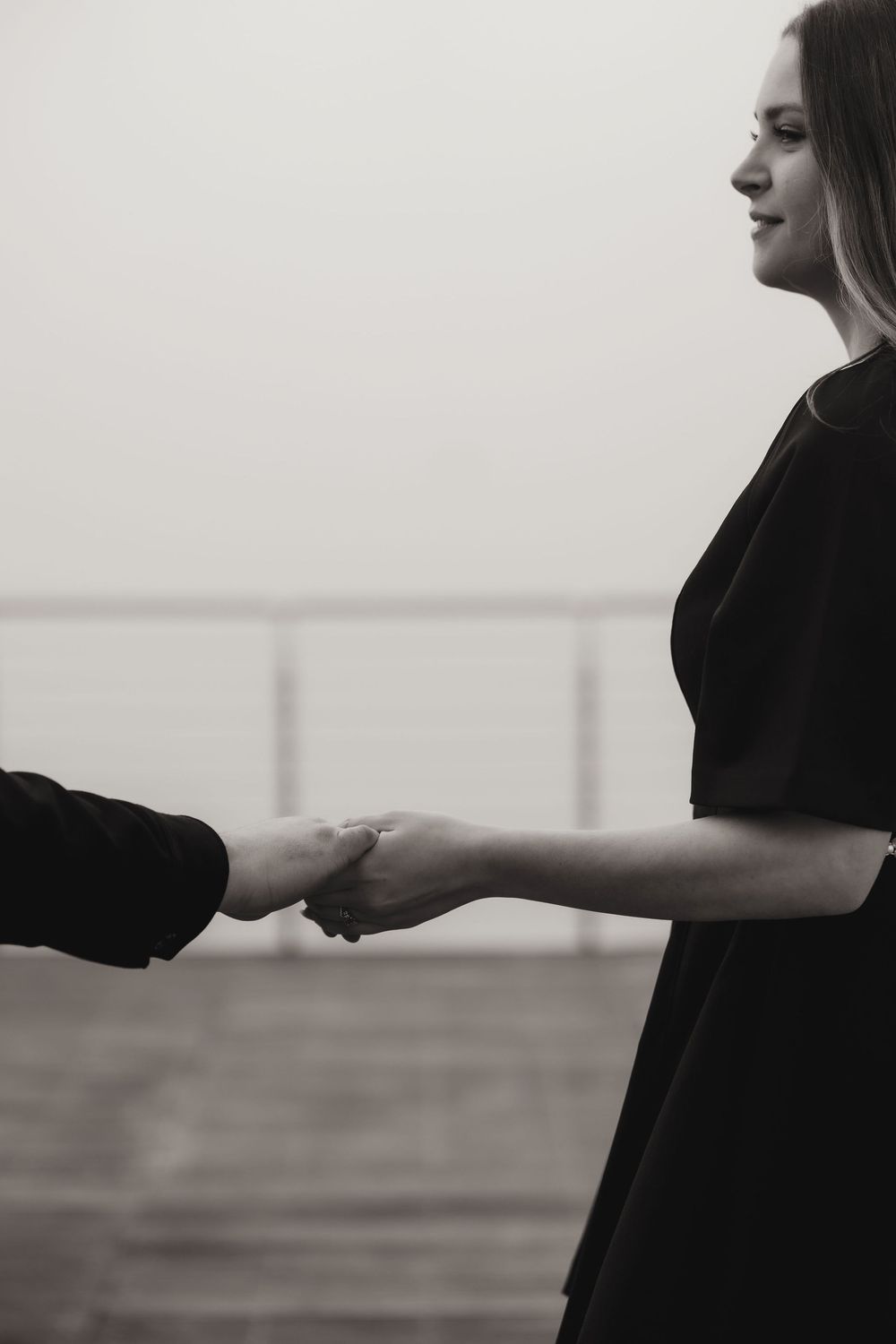 Elegant couple posing on a minimalist balcony in Portopiccolo, moody and timeless vibe.