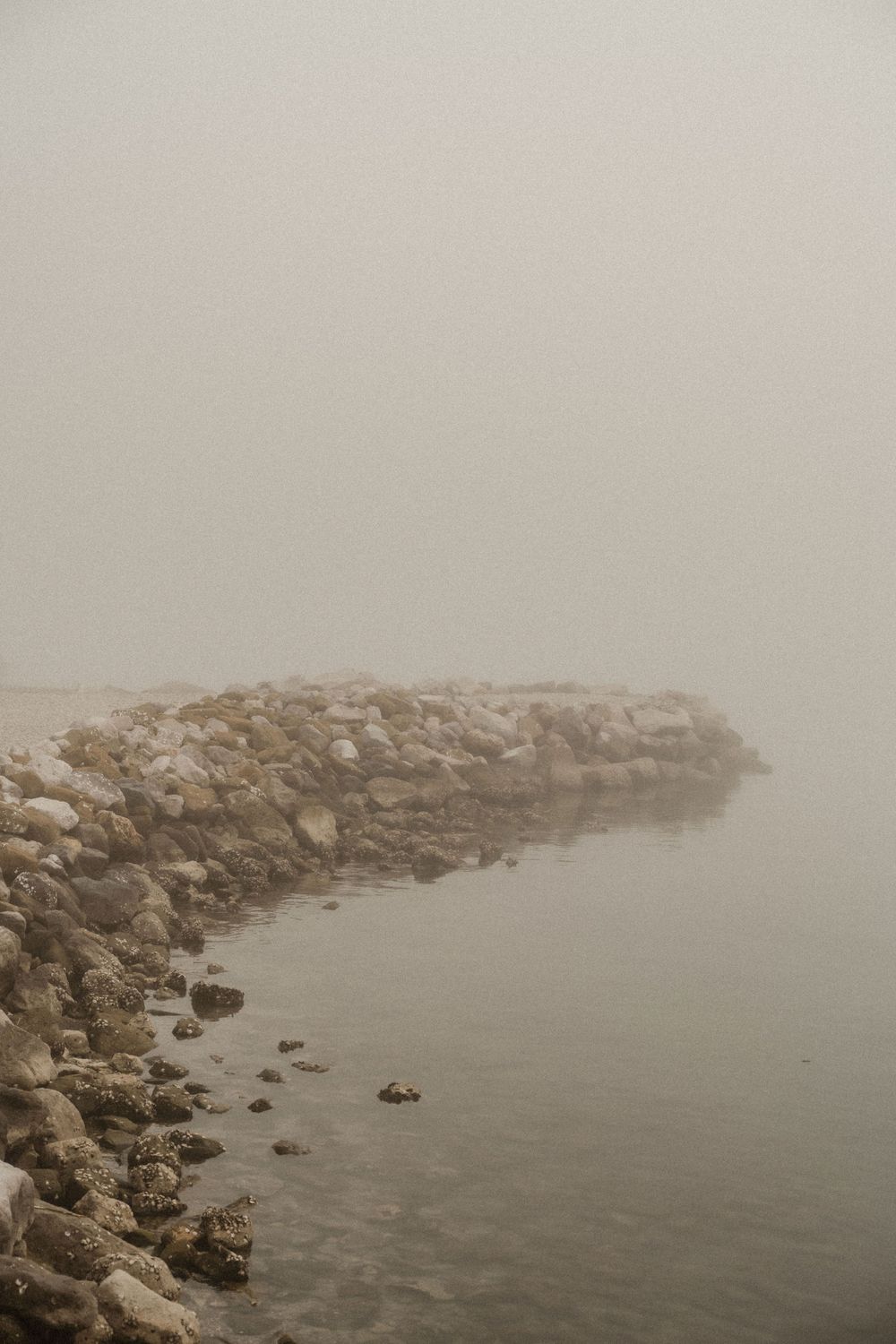 Couple looking out from a luxury terrace in Portopiccolo with the sea hidden by fog.