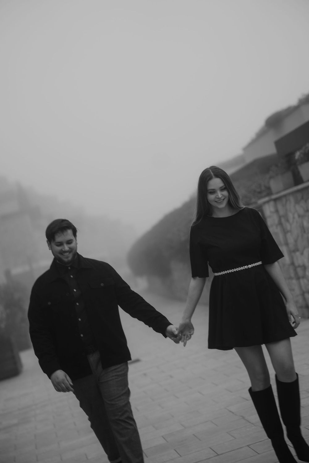 Romantic couple framed by the clean lines of Portopiccolo village on a foggy morning.