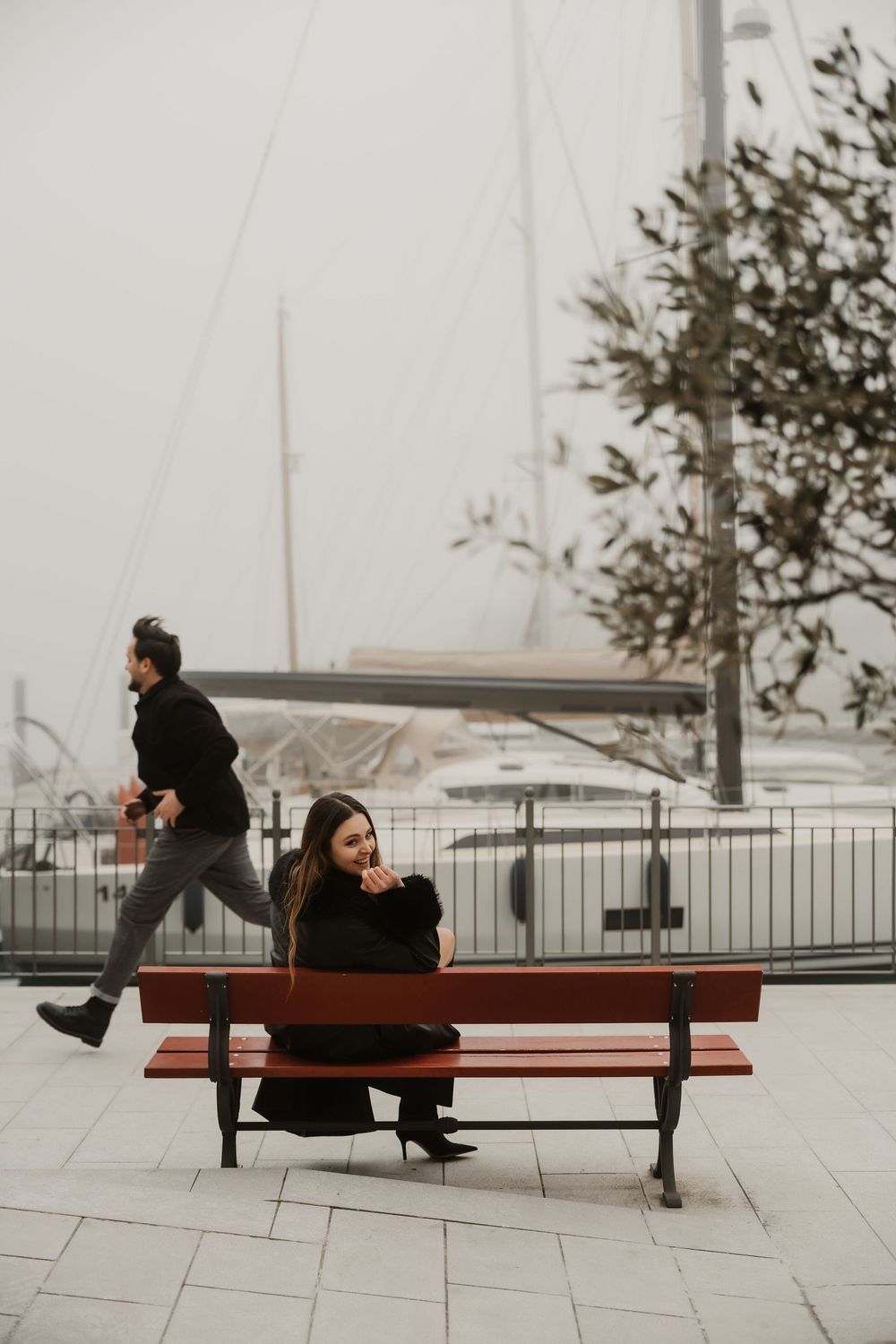 Cinematic portrait of a foreign couple walking down the stone alleys of Portopiccolo in the fog.