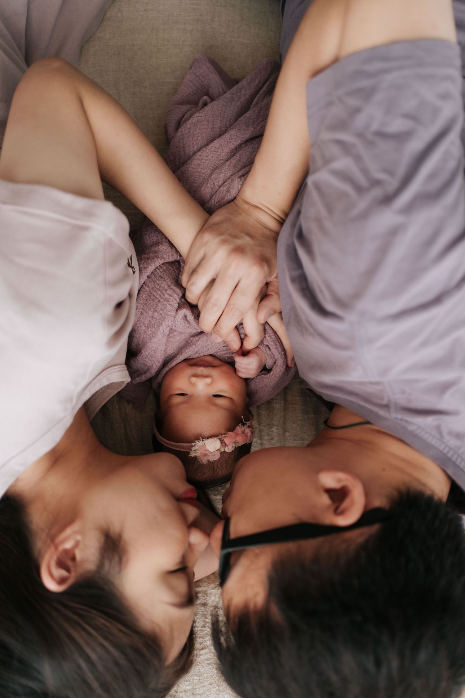 Two people lying close together on gray bedding share an intimate moment in a romantic lifestyle photo series.一組浪漫的生活照中,兩個人依偎在灰色的床單上