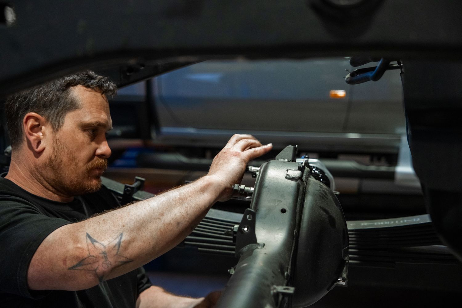 Automotive technician working on a vehicle in a professional workshop.