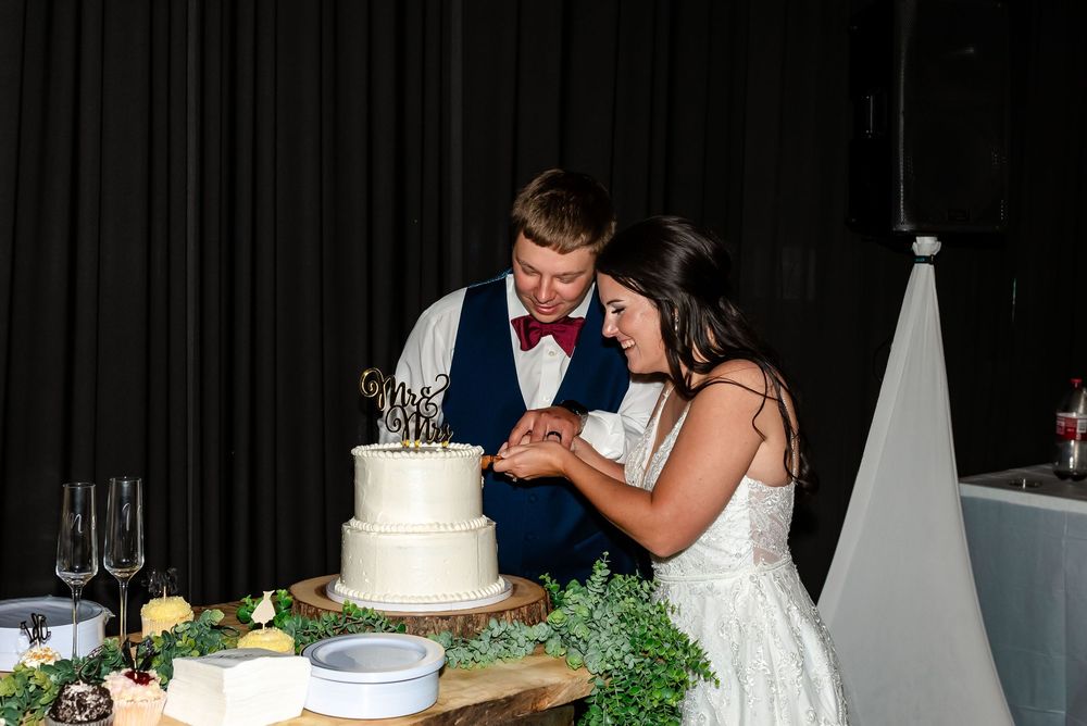 Bride and groom cutting their white two-tier wedding cake together at their reception.