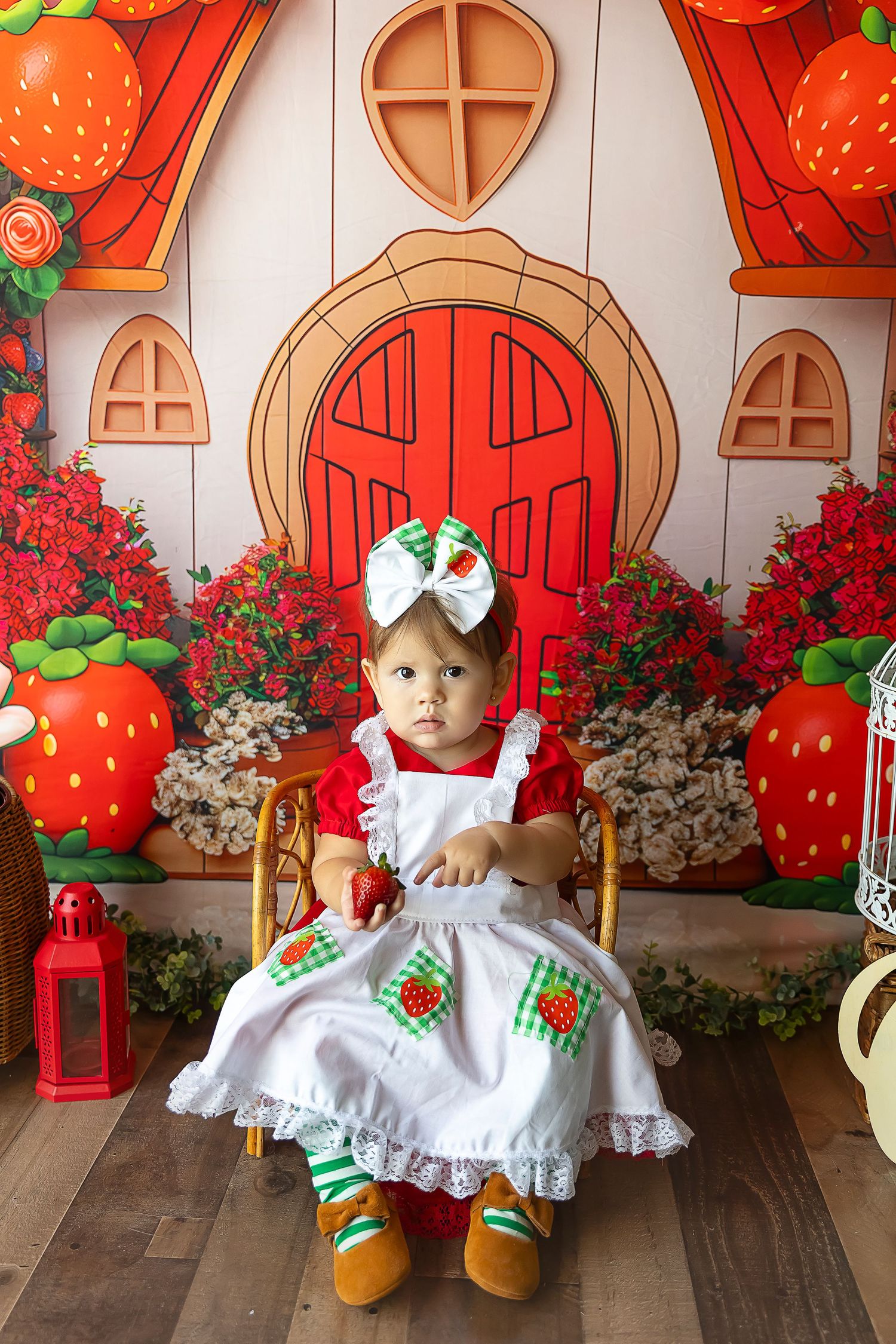 Fotografa infantil en ponce sesion de strawberry shortcake en estudio bebe apuntanto a una fresa en su mano