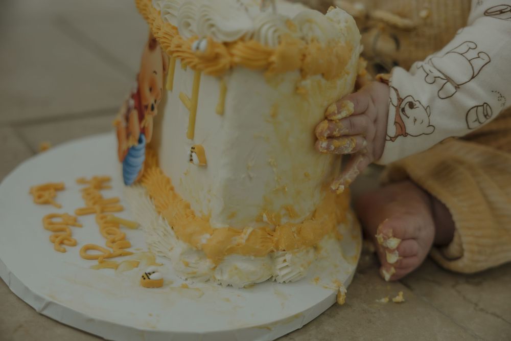 Baby hands smashing a white and gold first birthday cake during a cake smash photoshoot. Bismarck, ND photographer