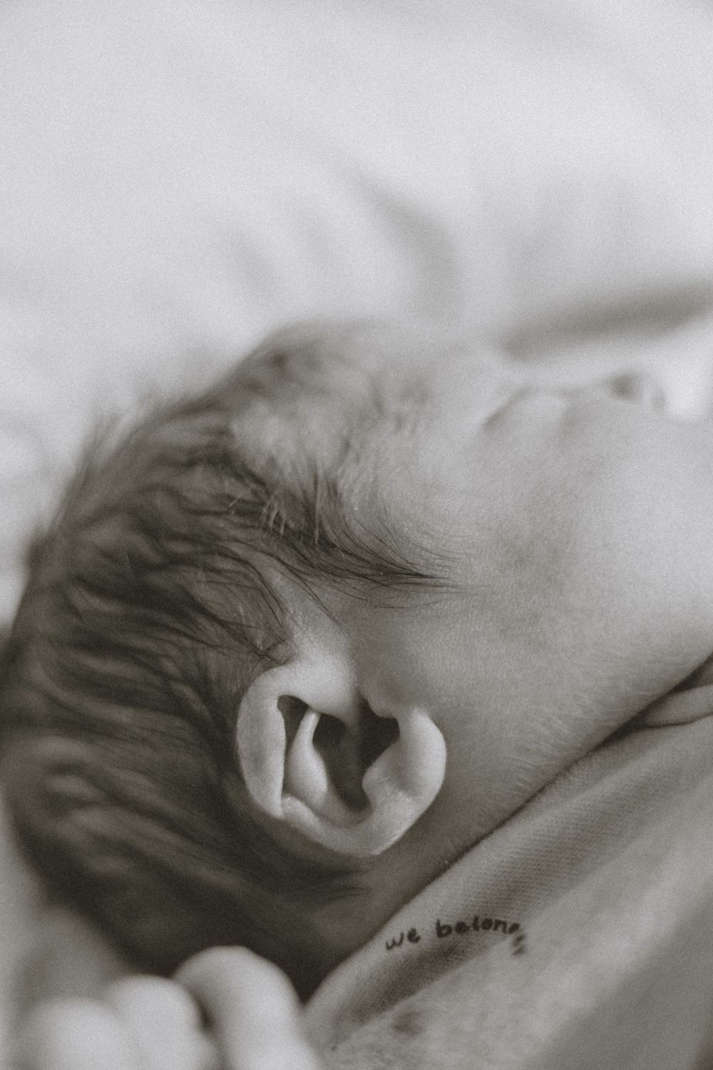 Black and white close-up photo of a sleeping newborn baby with delicate features and fine hair. Bismarck, ND photographer
