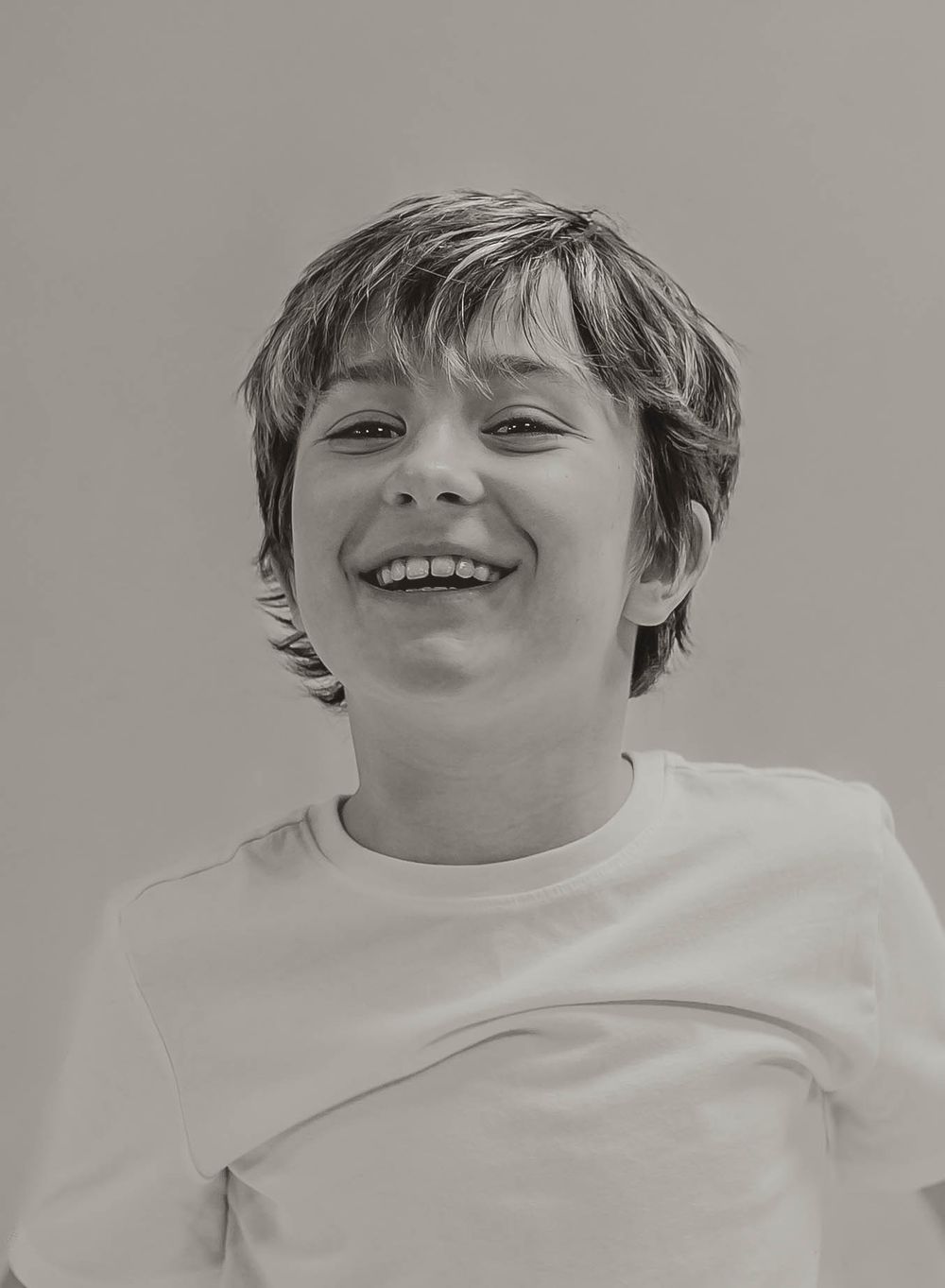 Black and white portrait of a happy smiling young boy with short hair wearing a white t-shirt. Garrison, ND Photographer