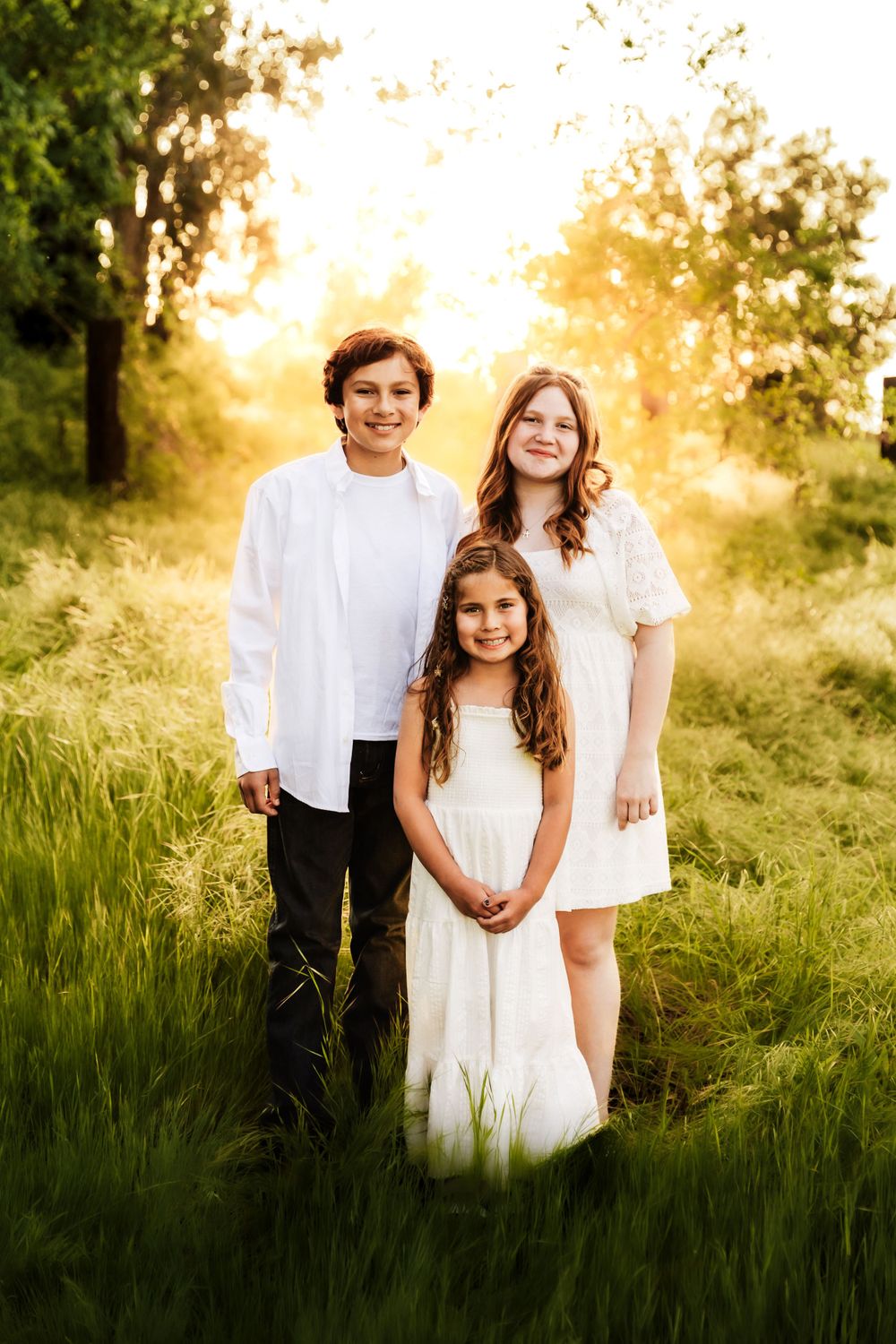 Landscape shot of lovely siblings surrnded of trees and a touch of golden hour sun in Fresno, CA."