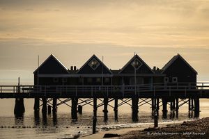Silhouetted image of Busselton Pier, Western Australia at sunset with a dramatic cloudy sky and silver waves