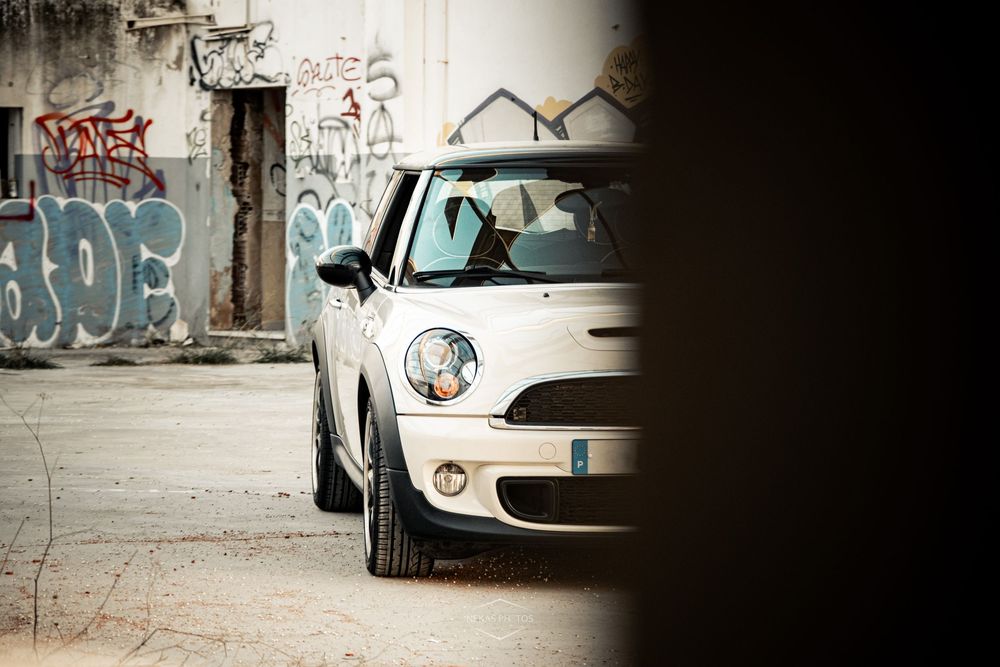 White Mini Cooper parked near graffiti-covered walls in an urban setting.