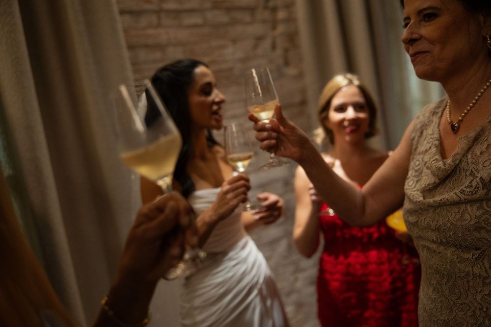 Bride and bridesmaids toasting with champagne glasses at a wedding celebration indoors.