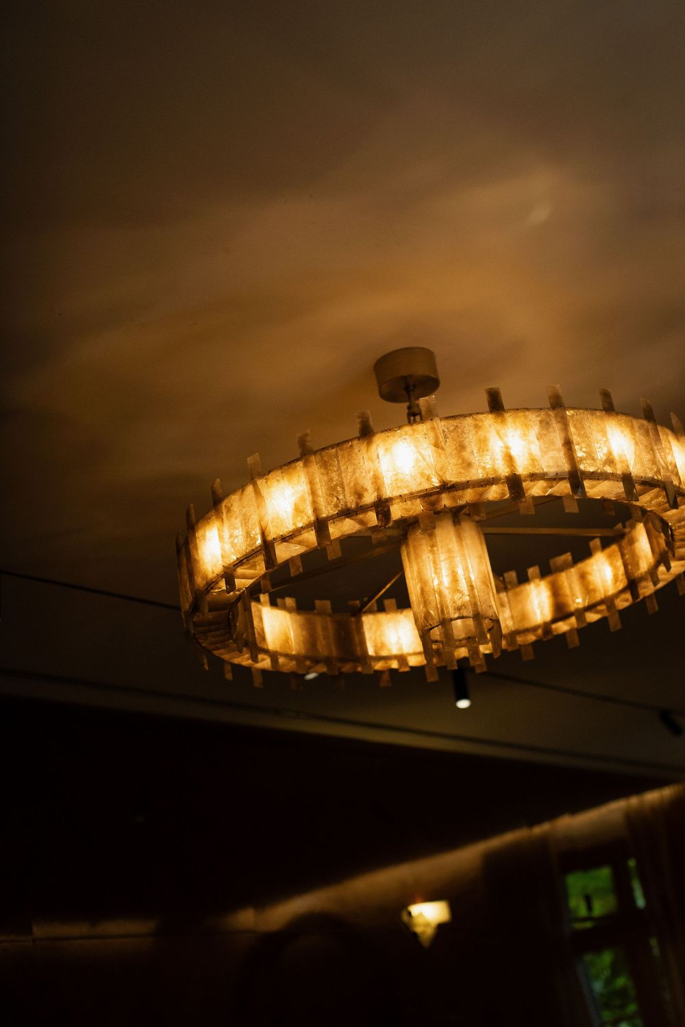 Elegant circular chandelier with warm glowing lights hanging from a dark ceiling in a dimly lit interior space.