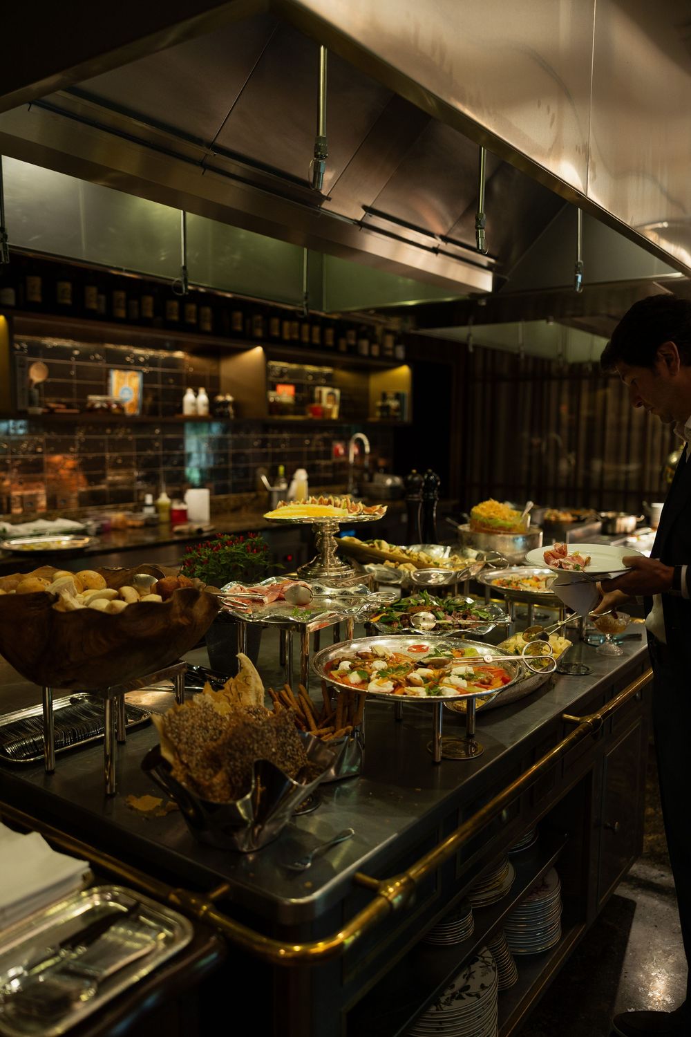 Elegant restaurant buffet spread with diverse dishes on dark counter, professional kitchen in background.