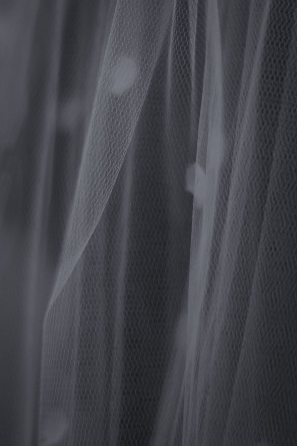 Soft gray tulle fabric with delicate folds and sheer texture, creating an elegant draped effect.