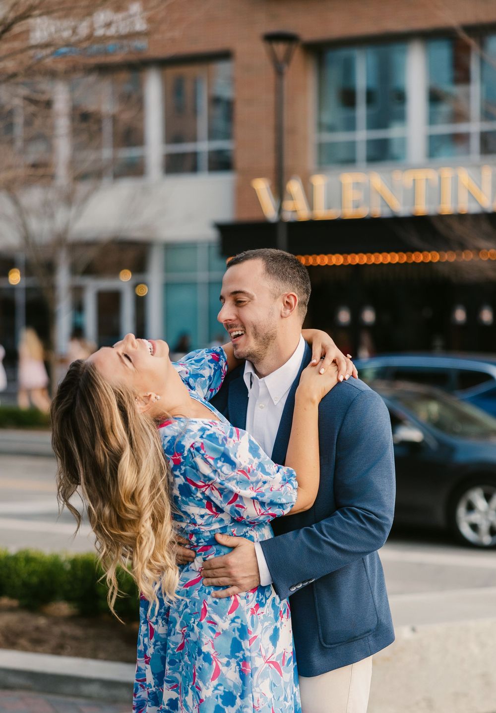 Happy couple embracing and laughing together outside the Valentine restaurant in a charming city setting. Valentinos bridge park