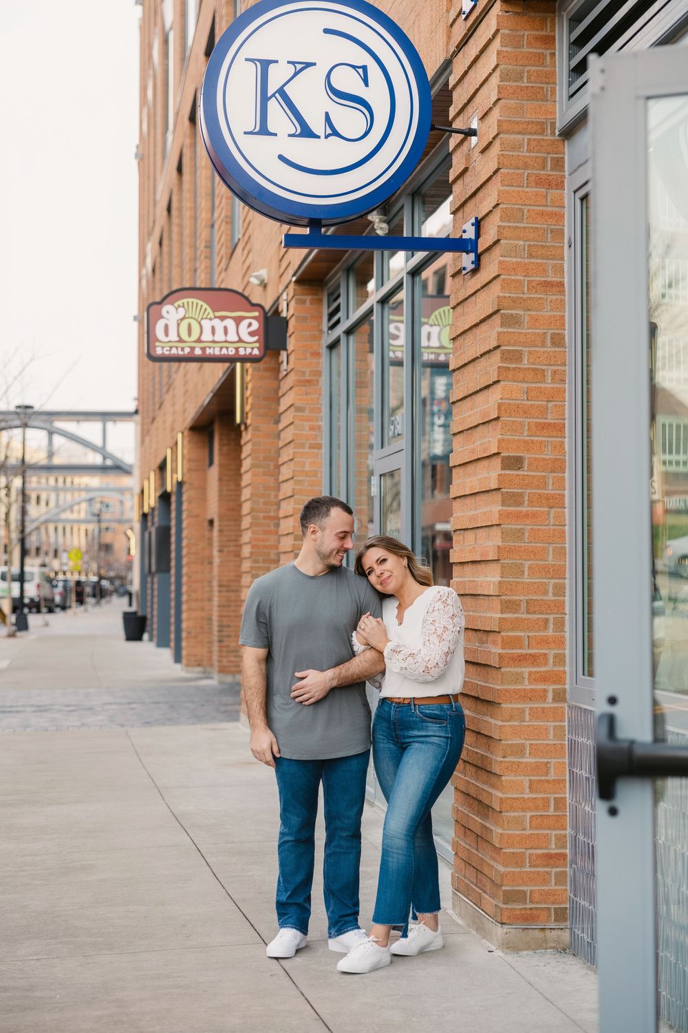 Happy couple embracing and laughing outside a brick building with KS sign. kitchen social