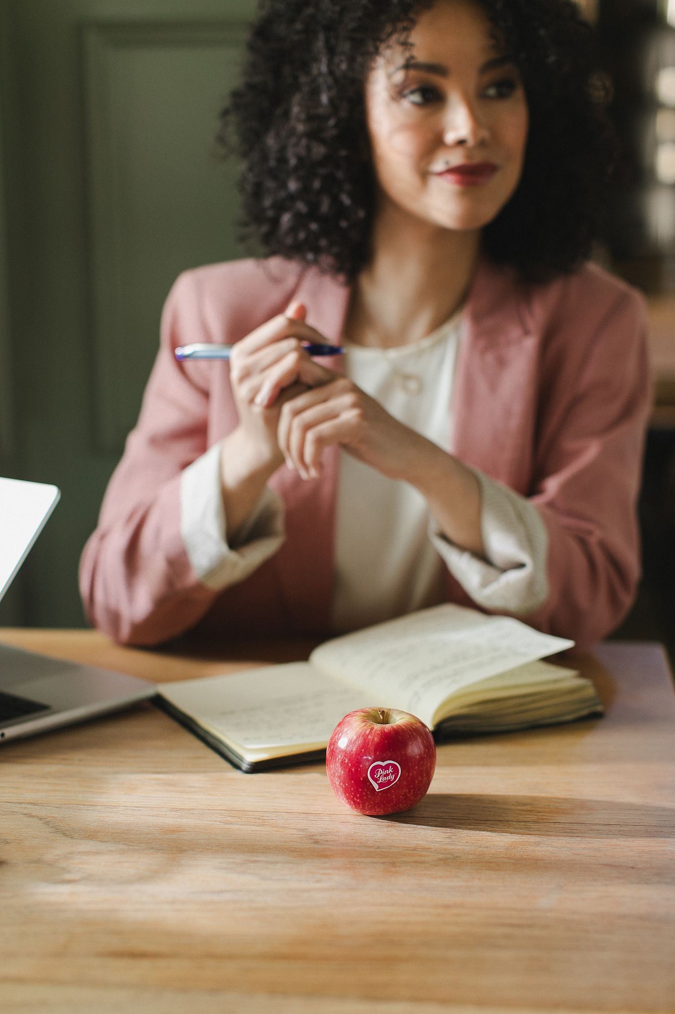 Fresh Pink Lady apples with soft morning light casting gentle shadows across a wooden surface.