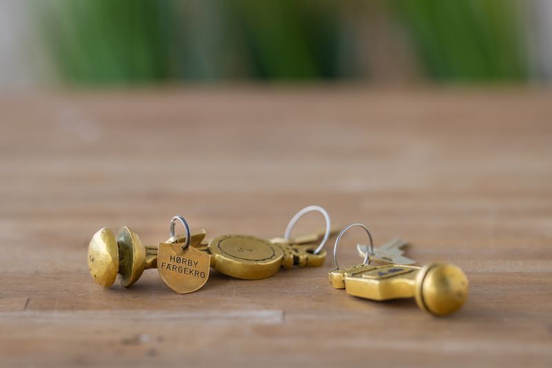 Gold brass keychains with round pendants and small keys arranged on a wooden table surface.