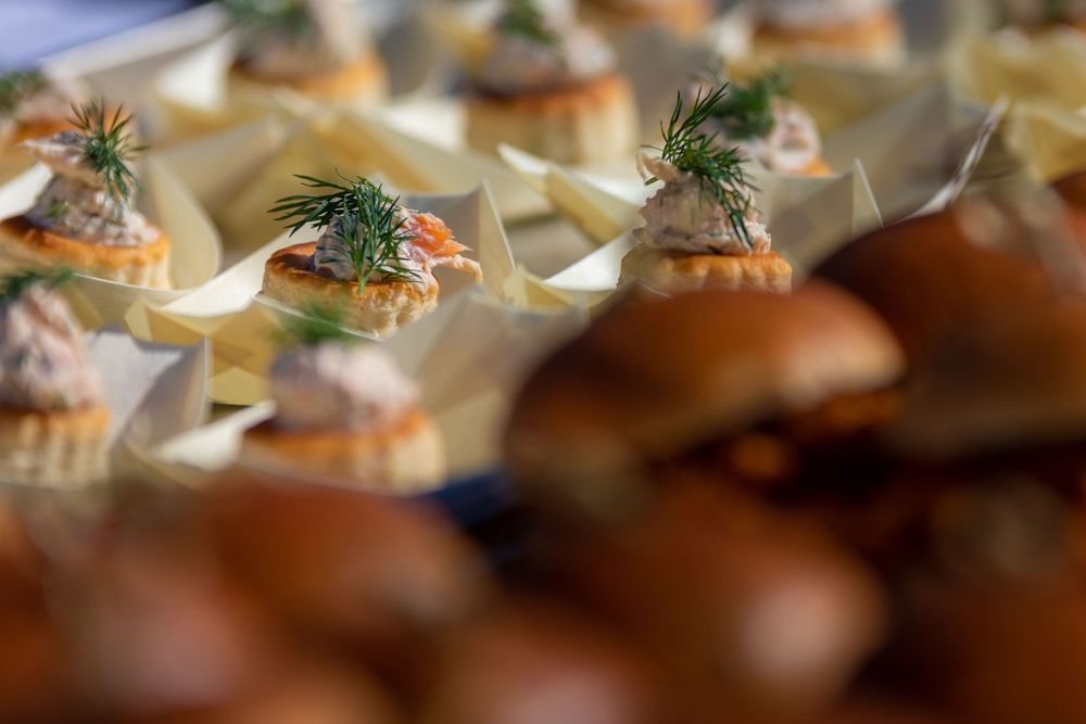 Elegant catering spread featuring gourmet appetizers with dill garnish in phyllo cups alongside fresh slider rolls.