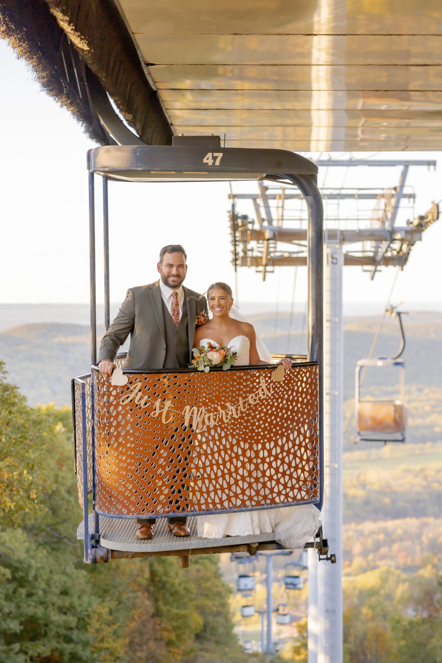 A newlywed couple smiles from a ski lift gondola decorated with a just married sign at Mountain Creek in Vernon, NJ.