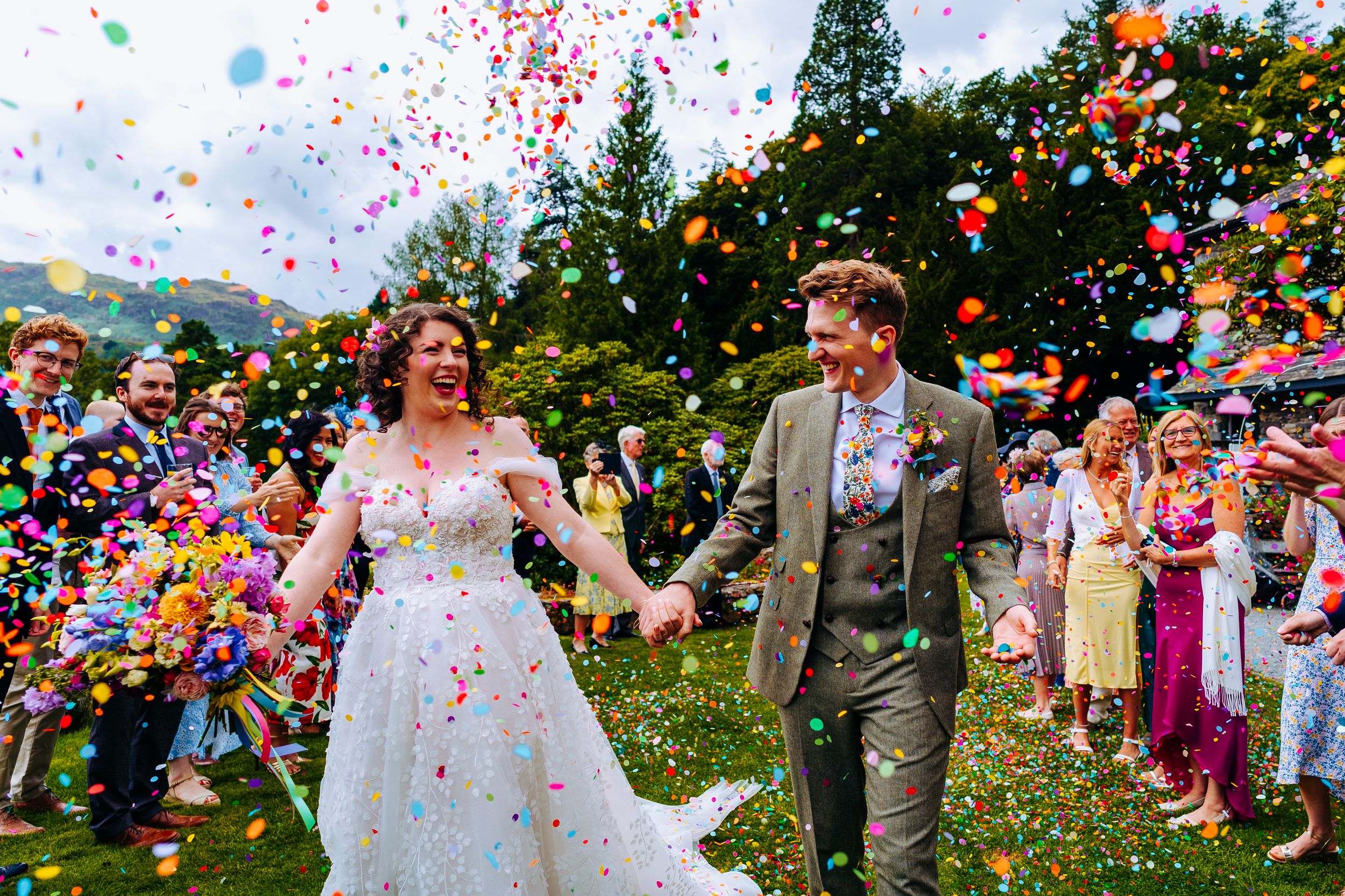 Colourful wedding confetti being thrown at a bride and groom
