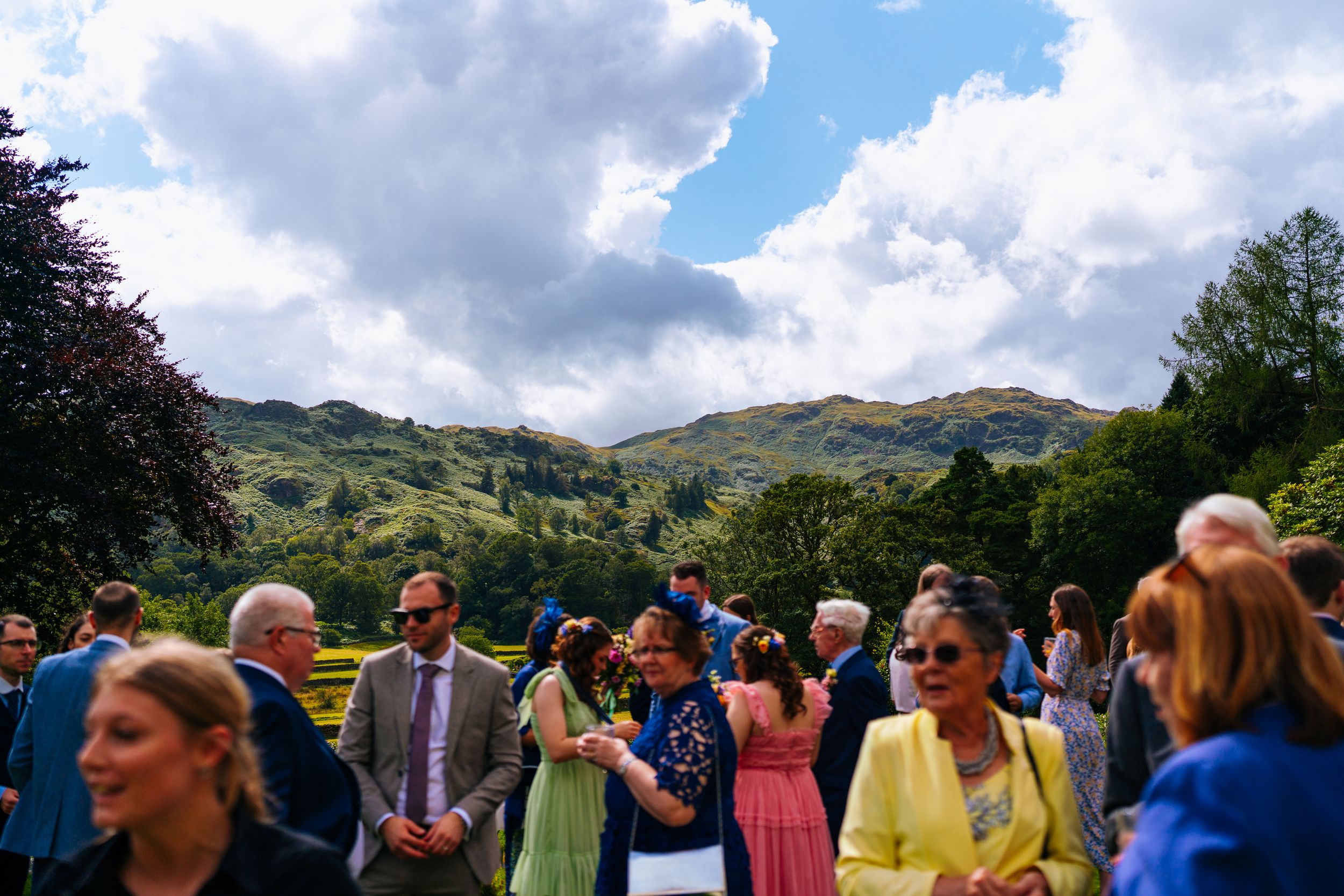 Wedding guests mingling during the reception with grasmere mountains overlooking them