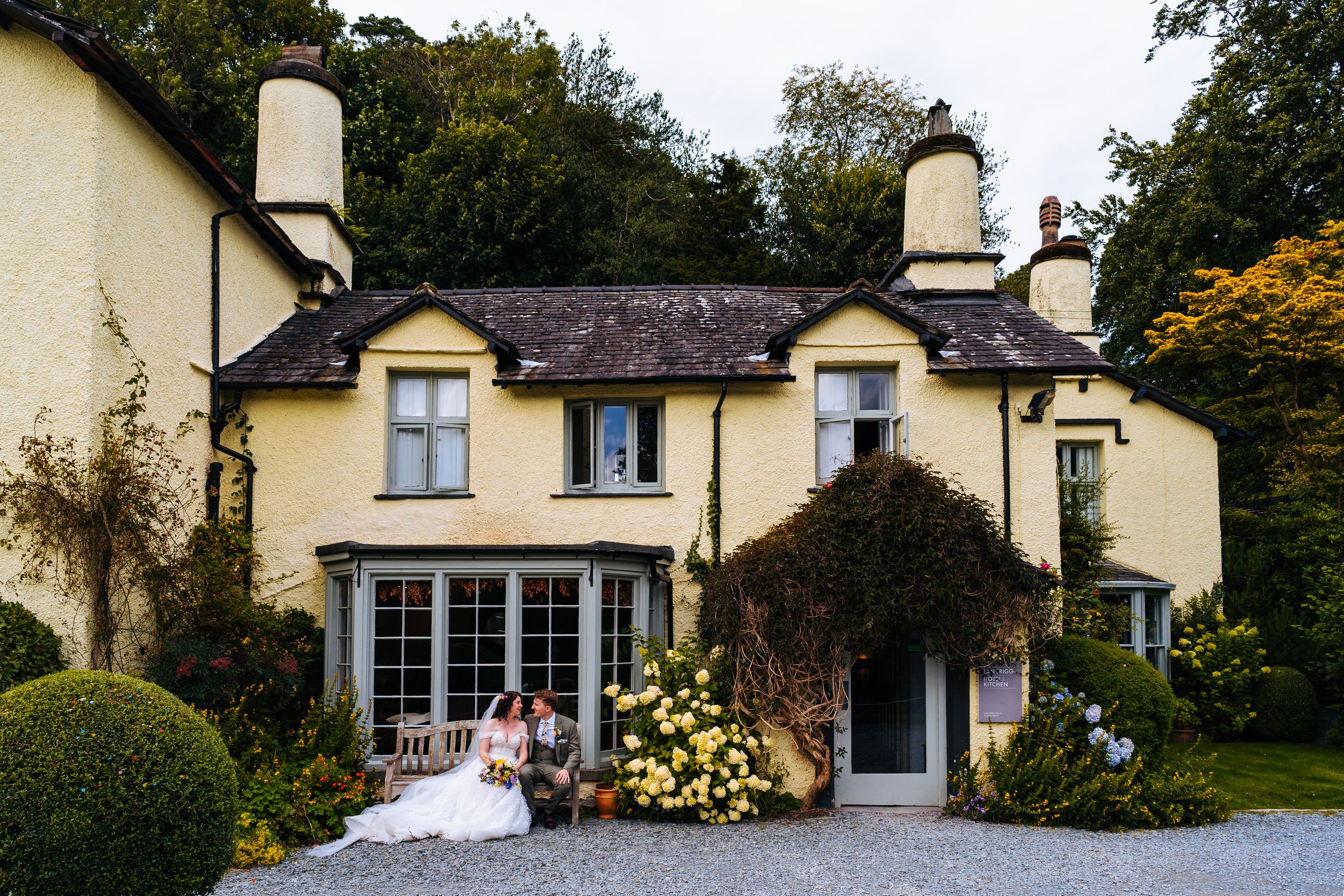 Bride and groom taking a moment together outside of the langrigg main house, cute lake district chocolate box style building with them