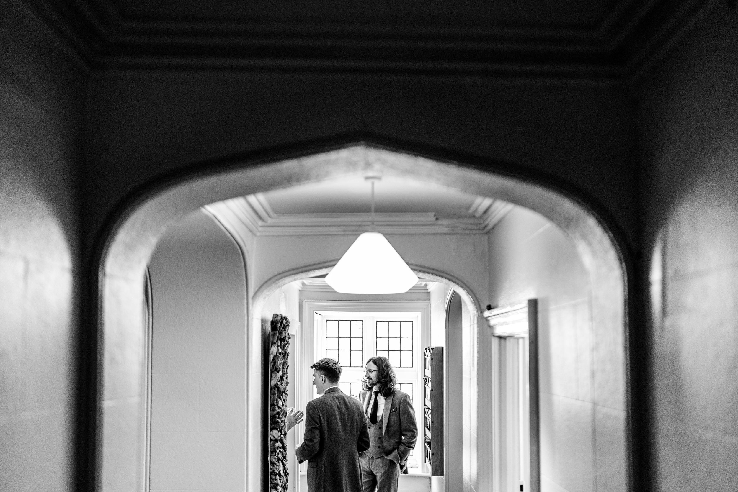 Two guests conversing in a grand hallway framed by an elegant arch in black and white.