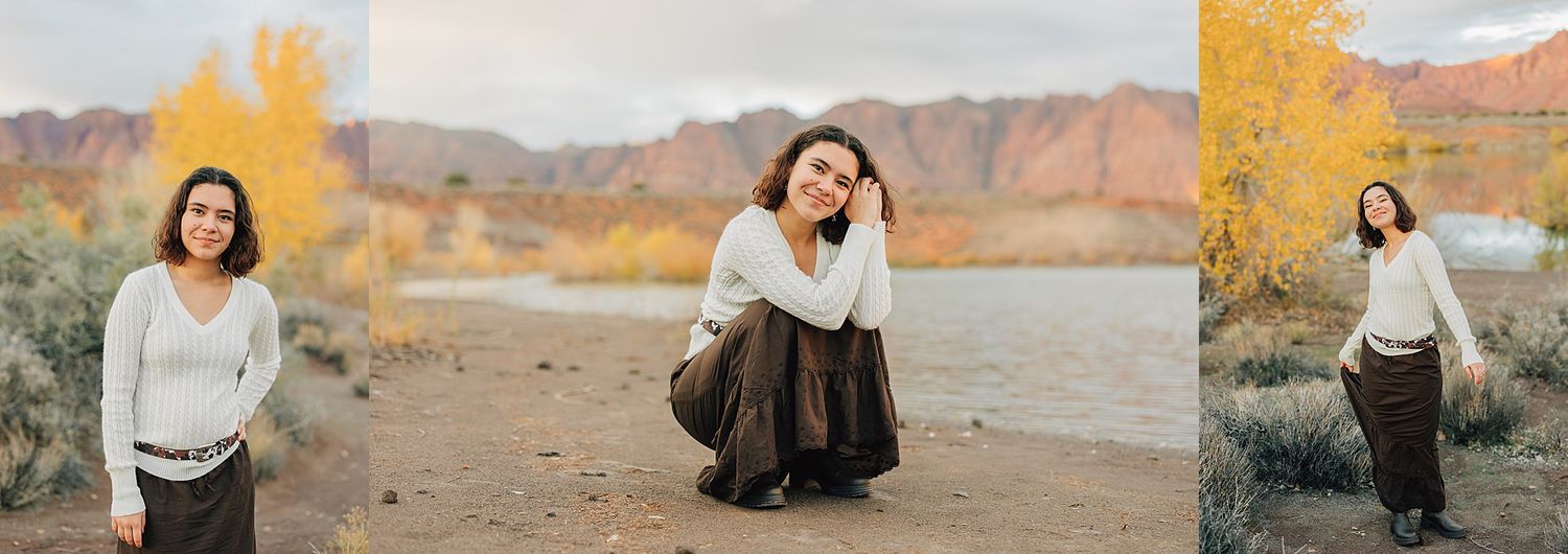 Young woman posing outdoors near a river with vibrant yellow autumn trees and red rock mountains in the background.
