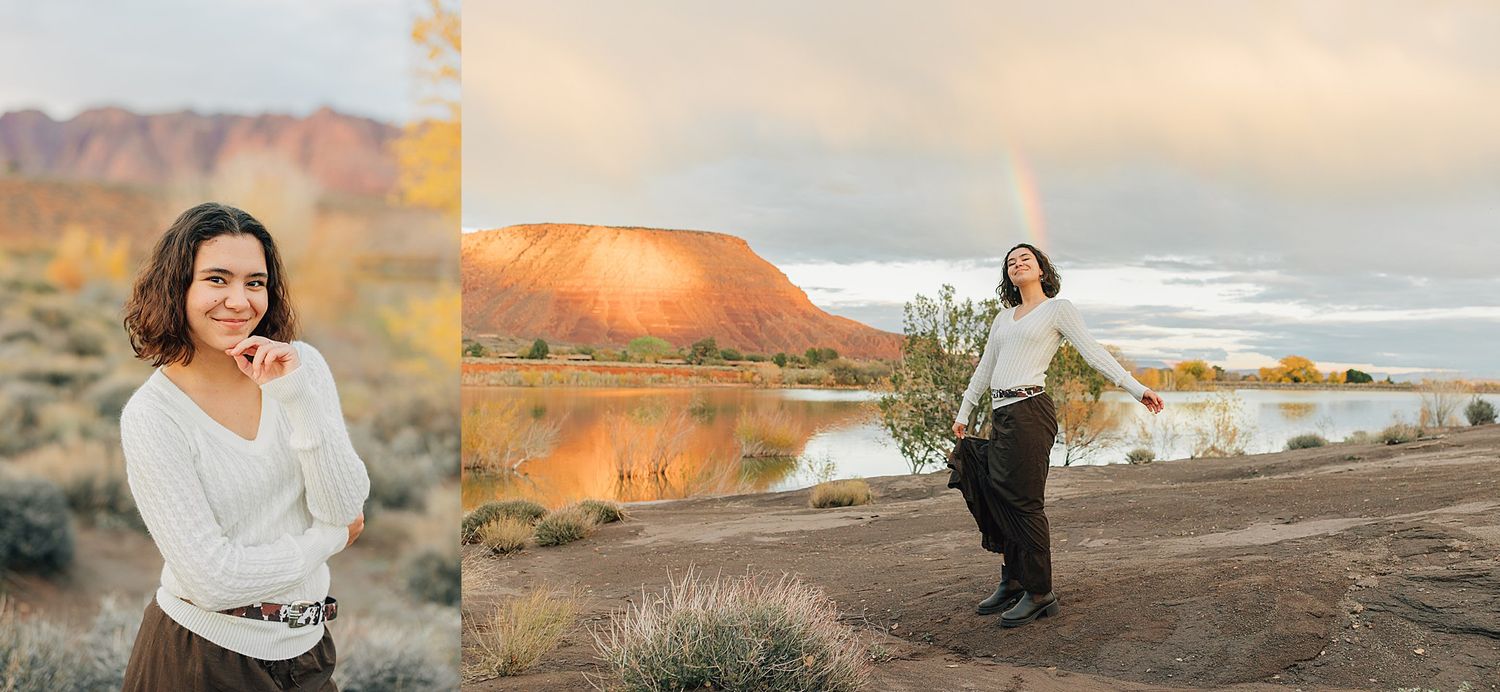 Young woman in white sweater poses near a colorful desert lake with a rainbow and red rock mountains at sunset.