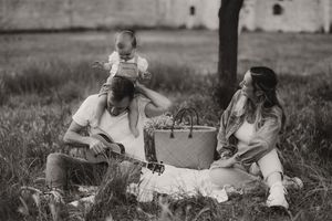 Family sharing joyful moments outdoors with guitar and picnic blanket.