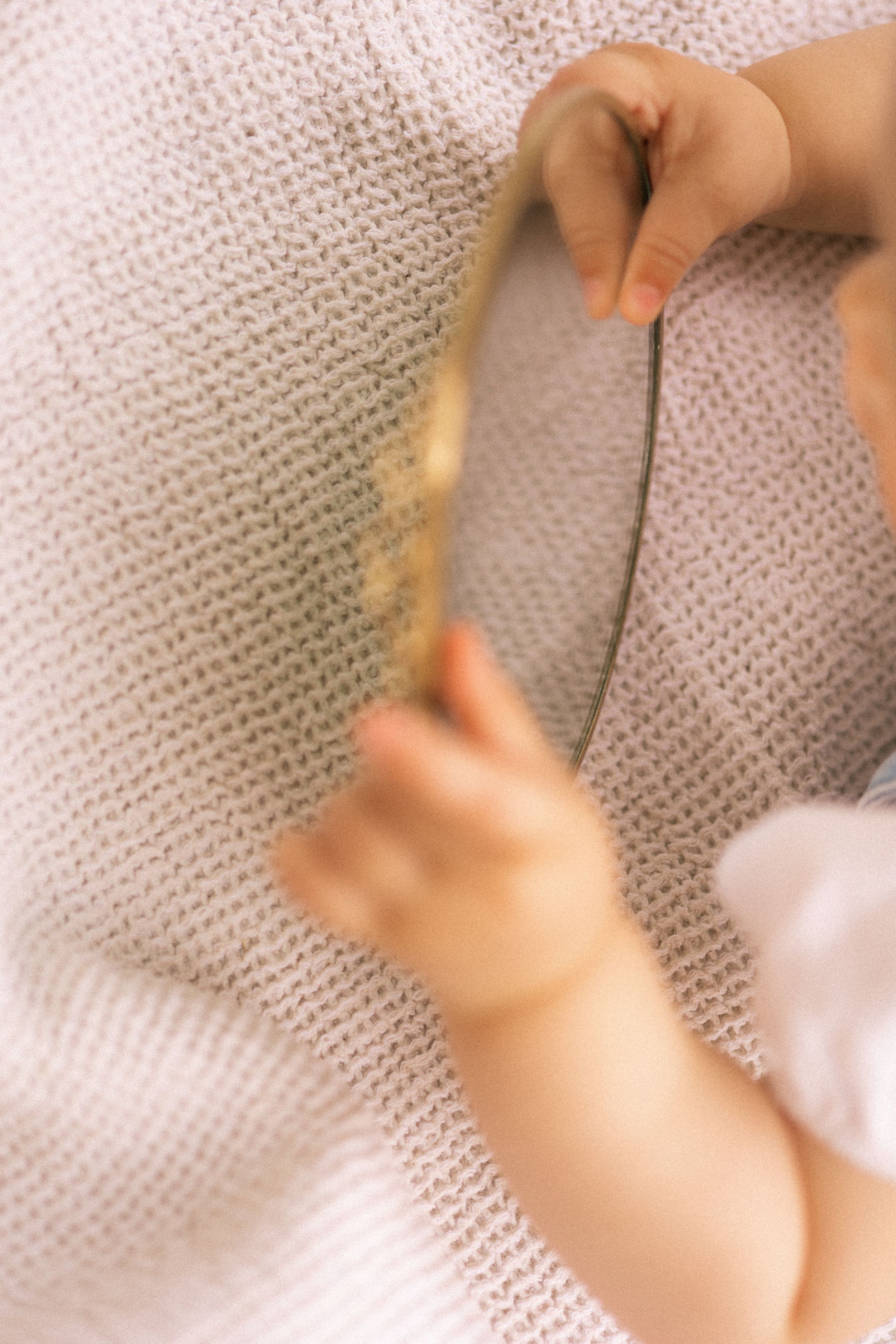 Small hands touching soft knitted fabric in dreamy macro shot.