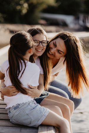 Candid outdoor photos showing joyful moments and embraces beside a lake at sunset.