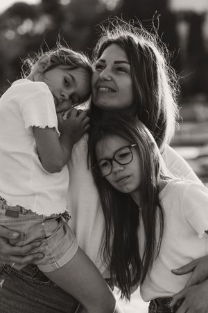 Black and white portrait capturing intimate group embrace outdoors.