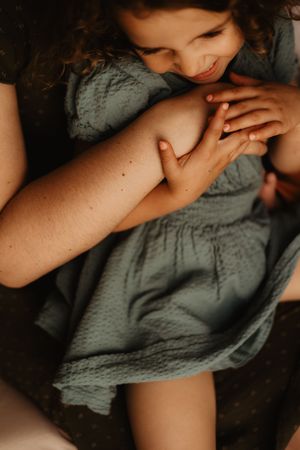Intimate close-up of someone in a sage green dress in soft lighting.