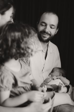 Black and white intimate family moment with newborn in soft lighting.