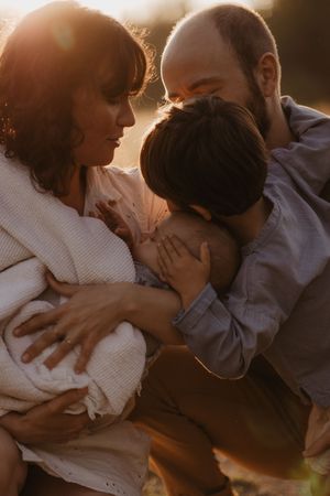 Intimate family embrace captured in golden sunset light.