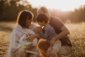 Family shares an intimate moment together in a sunlit field at golden hour.
