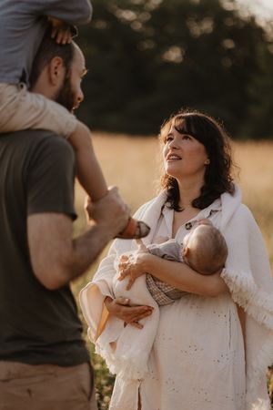 Family enjoying tender moment together in golden sunset field.