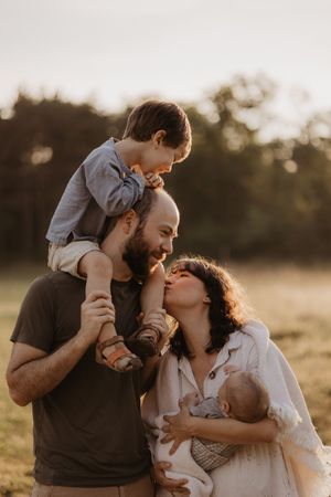 Young family sharing joyful moment together during sunset photoshoot.