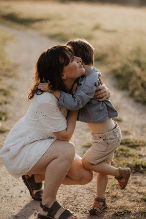 Tender moment between parent and child on sunny nature path.