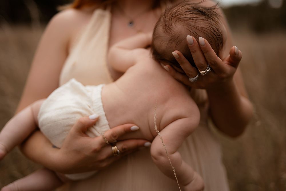Close-up shots of tender moments between a newborn baby and caregiver hands in warm, intimate lighting.