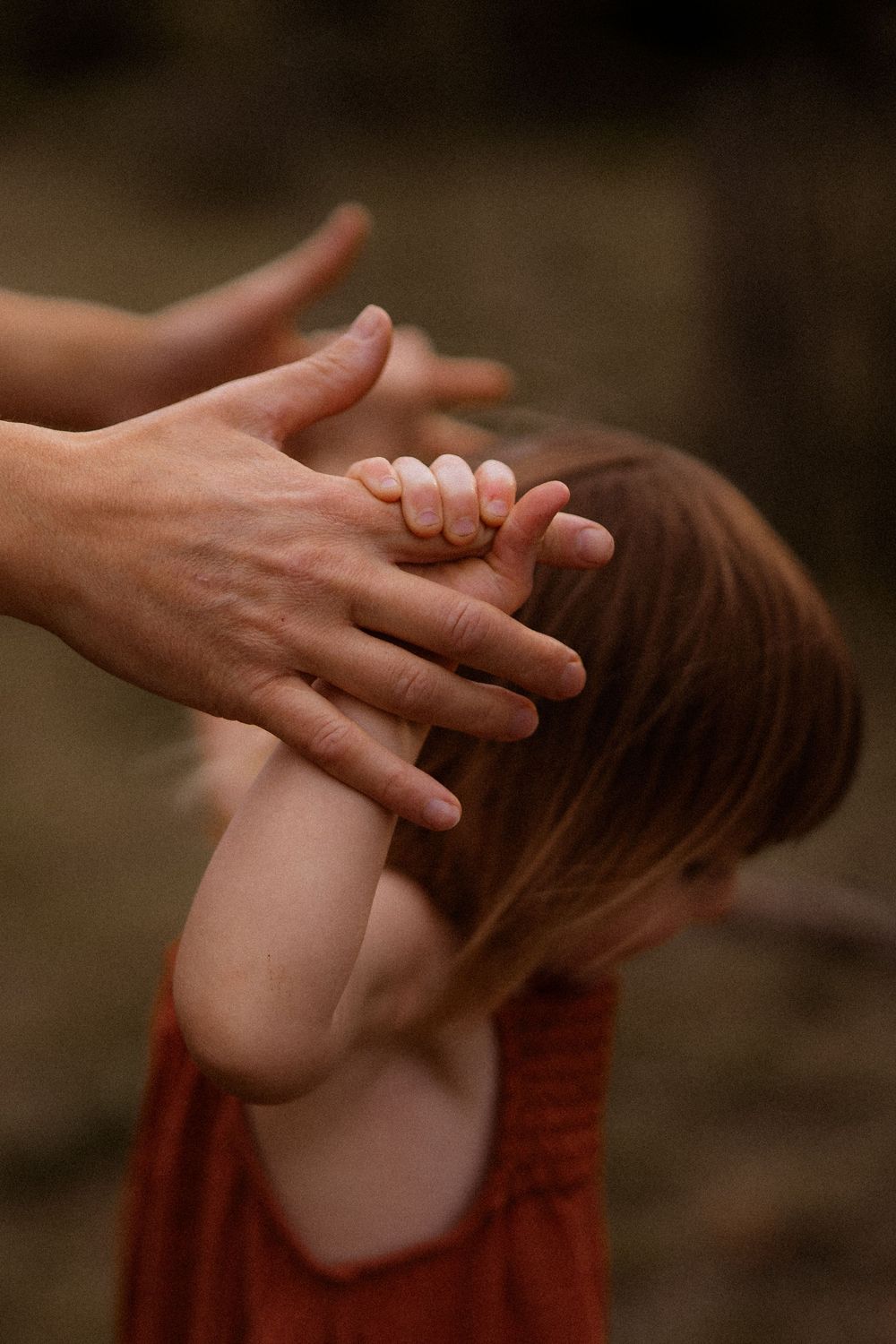 A series of hands reaching out in a dance-like sequence against a dark background in red tones.